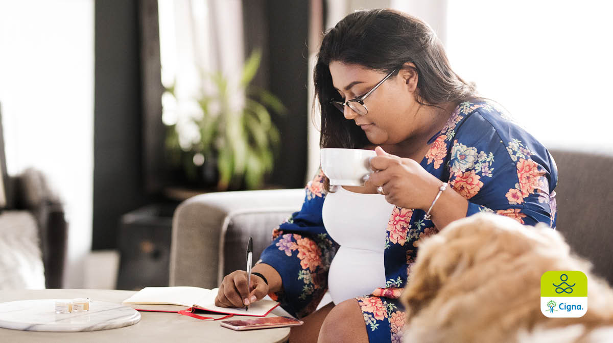 woman taking notes and having a cup of tea